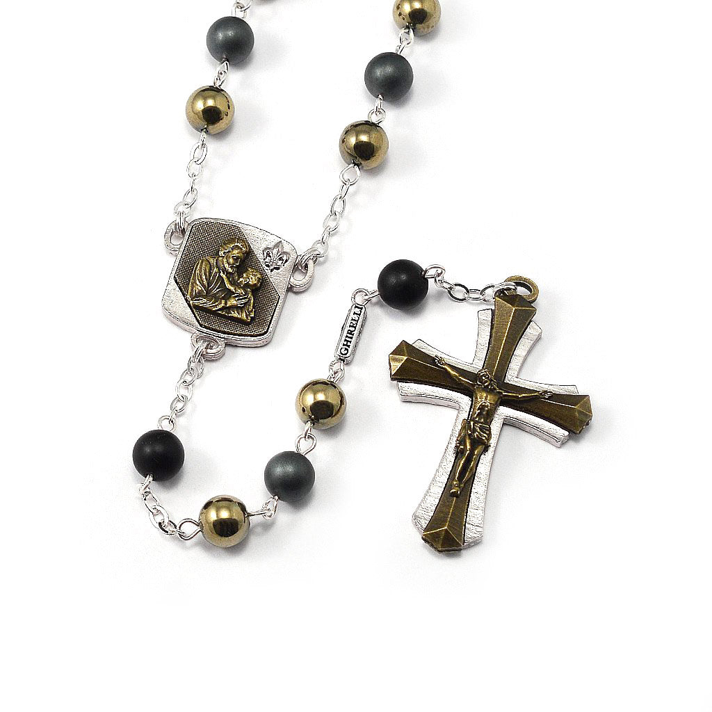 A rosary with bronze and silver finishes, and hematite beads, featuring a centerpiece with an image of Saint Joseph and a cross.